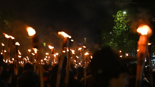 Статуя Мать Армения видна сквозь огонь факелов во время факельного шествия (23 апреля 2025). Еревaн - Sputnik Армения