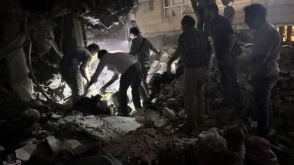 Спасатели на месте взрыва после израильской атаки в районе Нармак (15 июня 2025). Тегеран - Sputnik Армения