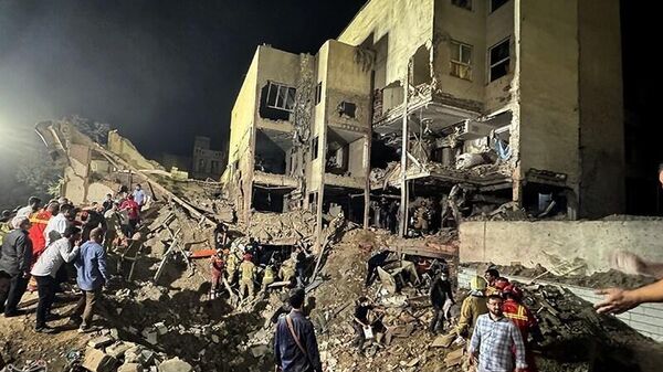 Спасатели на месте взрыва после израильской атаки в районе Нармак (15 июня 2025). Тегеран - Sputnik Армения