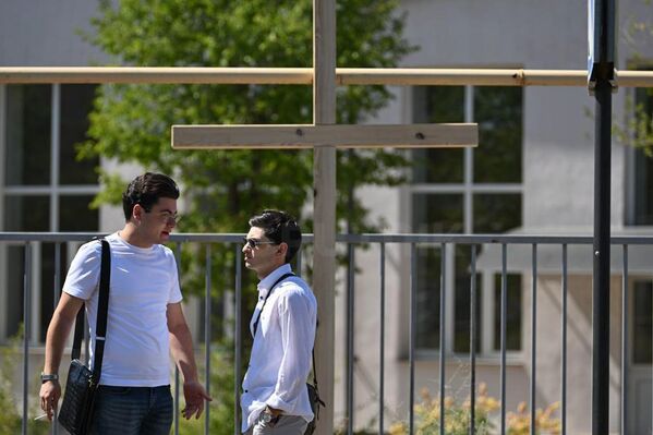 Молодые люди стоят возле креста во время судебного заседания по делу предстоятеля Ширакской епархии архиепископа Микаэла Аджапахяна - Sputnik Армения