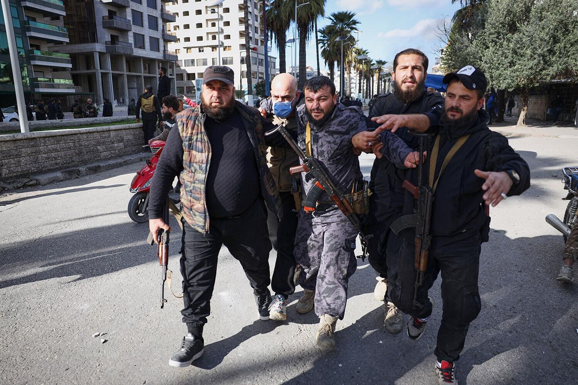 Раненного полицейского уводят с места происшествия после столкновений между протестующими алавитами и контр-протестующими (28 декабря 2025). Сирия - Sputnik Армения, 1920, 28.12.2025