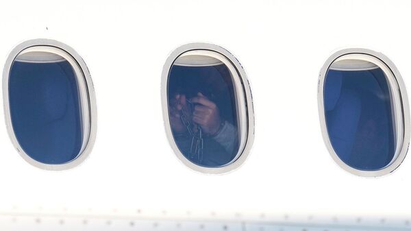 Депортированный из США мужчина демонстрирует свои руки в наручниках и цепях после приземления - Sputnik Армения