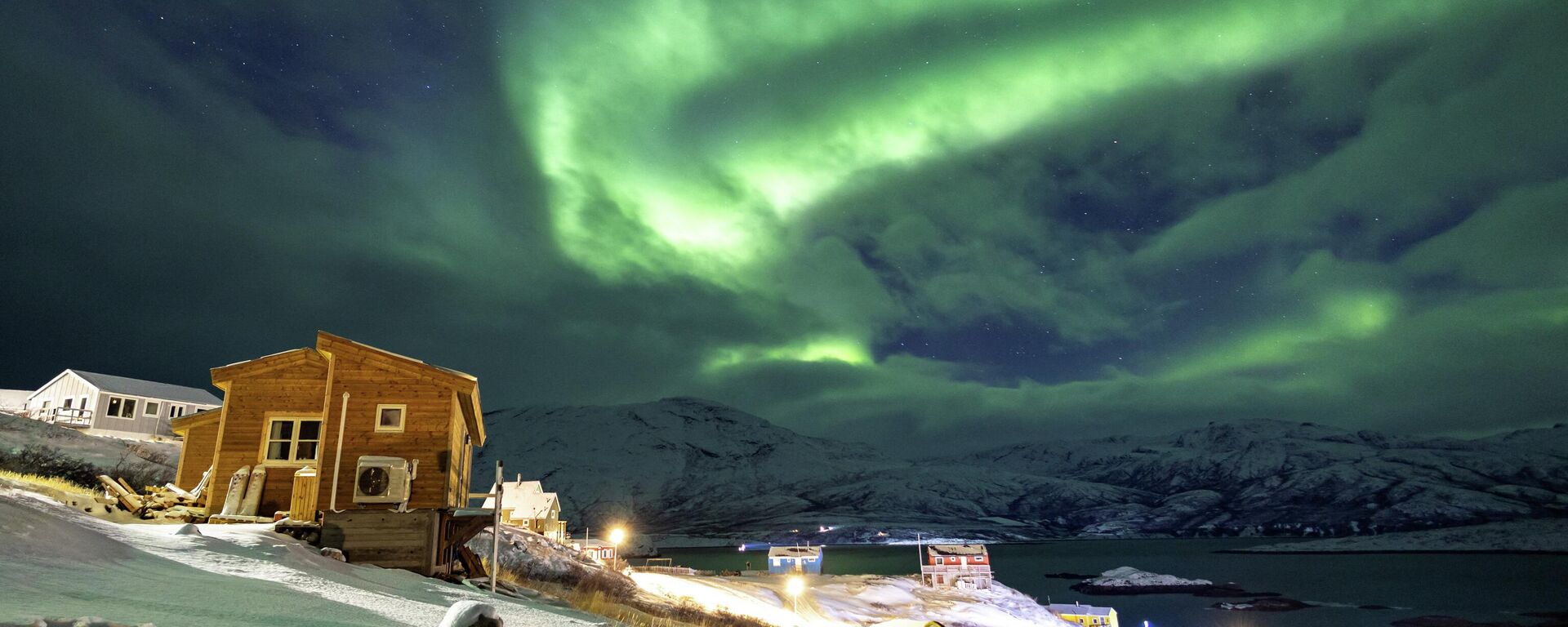 Северное сияние освещает небо над домами в Каписиллите, Гренландия - Sputnik Արմենիա, 1920, 30.01.2026