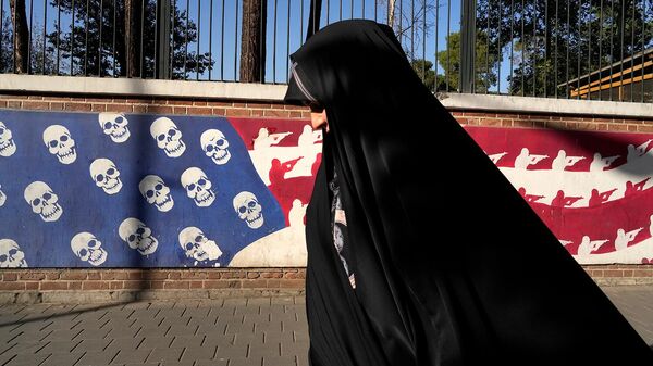 Иранка проходит мимо граффити в цветах и стиле американского флага на стене бывшего посольства США в Иране (22 октября 2024). Тегеран - Sputnik Армения