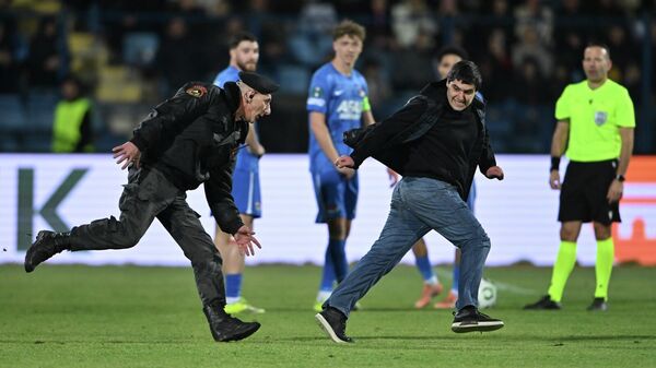 Охранник бежит за правонарушителем, выбежавшим на поле во время матча плей-офф Лиги конференций (1/16 финала) между командами “Ноа (Армения) и АЗ Алкмар” (Нидерланды) на стадионе Вазгена Саркисяна (19 февраля 2026). Еревaн Охранник бежит за правонарушителем, выбежавшим на поле во время матча плей-офф Лиги конференций (1/16 финала) между командами “Ноа (Армения) и АЗ Алкмар” (Нидерланды) на стадионе Вазгена Саркисяна (19 февраля 2026). Еревaн - Sputnik Армения