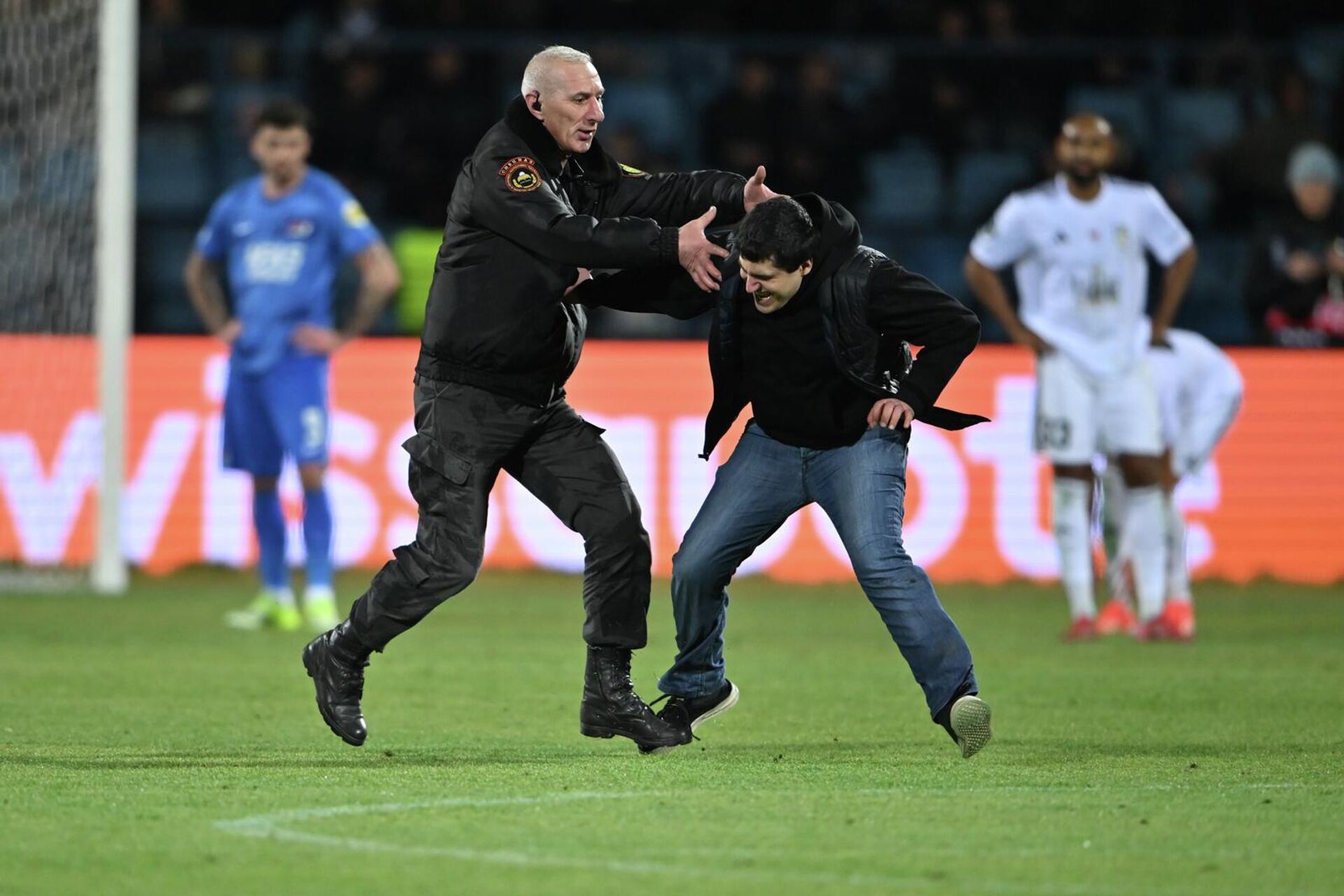 Охранник ловит правонарушителя, выбежавшего на поле во время матча плей-офф Лиги конференций (1/16 финала) между командами “Ноа (Армения) и АЗ Алкмар” (Нидерланды) на стадионе Вазгена Саркисяна (19 февраля 2026). Еревaн - Sputnik Армения, 1920, 20.02.2026