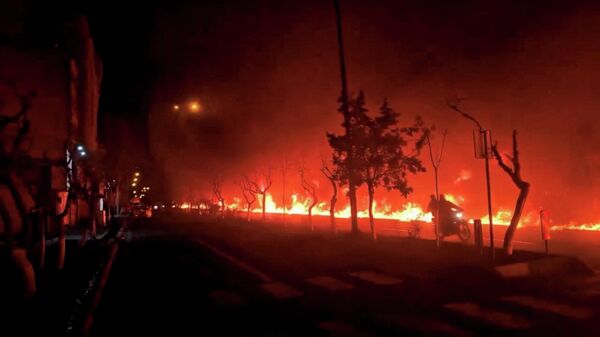 Мотоцикл проезжает мимо горящего бульвара Кохсар в Тегеране, Иран. - Sputnik Армения