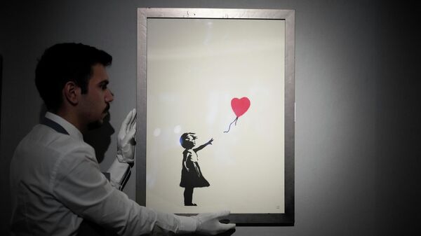 Сотрудник с репродукцией картины Девочка с воздушным шаром, 2004 британского уличного художника Бэнкси в аукционном доме Bonhams (8 ноября 2021). Лондон - Sputnik Армения