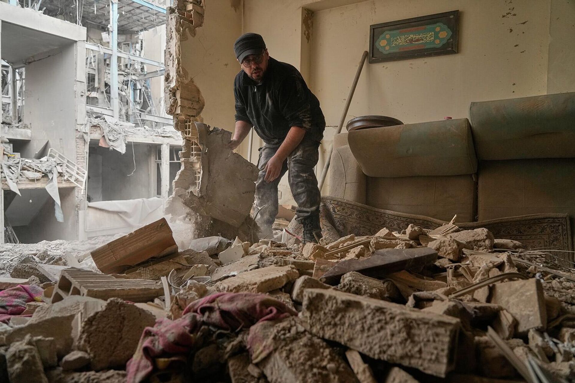 Мужчина убирает обломки из своей квартиры, поврежденной в результате американо-израильского удара по расположенному неподалеку полицейскому участку в Тегеране (15 марта 2026). Иран - Sputnik Армения, 1920, 16.03.2026