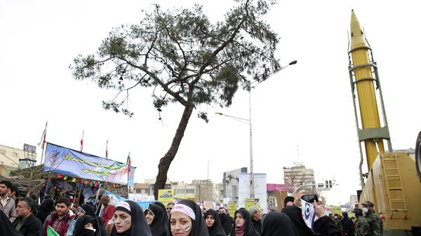 Иранцы на митинге, посвященном 37-й годовщине исламской революции, рядом с баллистической ракетой класса земля-земля большой дальности Emad в Тегеране, Иран - Sputnik Армения