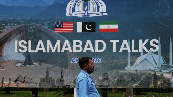 Полицейский проходит мимо рекламного щита, посвященного переговорам между США и Ираном, возле центра содействия СМИ в Исламабаде (11 апреля 2026). Пакистан - Sputnik Армения