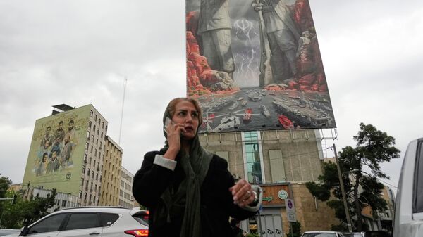 Женщина c мобильным телефоном на фоне плаката с изображением иранского военачальника Раиса-Али Дельвари и командующего ВМС КСИР Алирезы Тангсири в Тегеране, Иран - Sputnik Армения