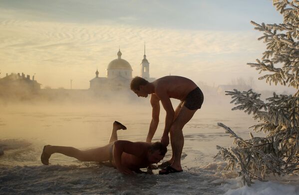 Мужчины окунаются после бани в проруби реки Великая в городе Остров Псковской области - Sputnik Армения