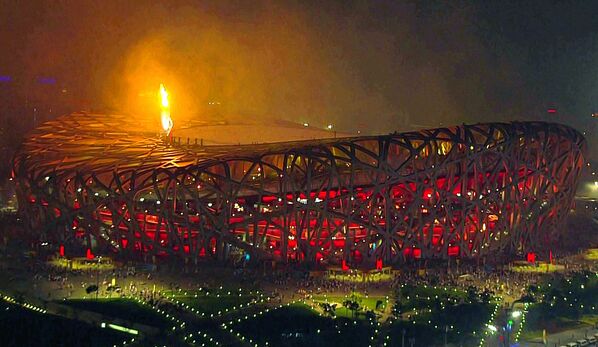 Олимпийский огонь освещает небо над национальным стадионом Пекина, также известный как Птичье гнездо (8 августа 2008). Пекин, Китай - Sputnik Армения