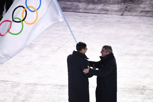 Պեկինի քաղաքապետ Չեն Ցզինինը (ձախից) և  ՄՕԿ–ի նախագահ Թոմաս Բախը Փհենչհանի XXIII ձմեռային օլիմպիական խաղերի փակման արարողության ժամանակ օլիմպիական դրոշը փոխանցելիս։ - Sputnik Արմենիա