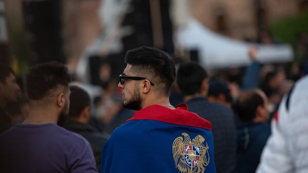 Герб Армении, изображенный на флаге Армении, обернутом гражданином Армении. - Sputnik Армения