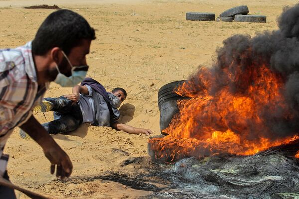 Палестинские протестующие сжигают шины во время столкновений с израильской армией вблизи границы с Израилем, к востоку от Рафаха в южной части сектора Газа в пятницу, 13 апреля 2018 года. - Sputnik Армения