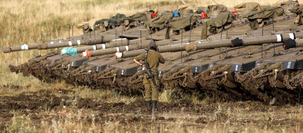 Израильский солдат рядом с танками Merkava Mark IV в районе развертывания вблизи сирийской границы (10 мая 2018). Голанские высоты - Sputnik Армения
