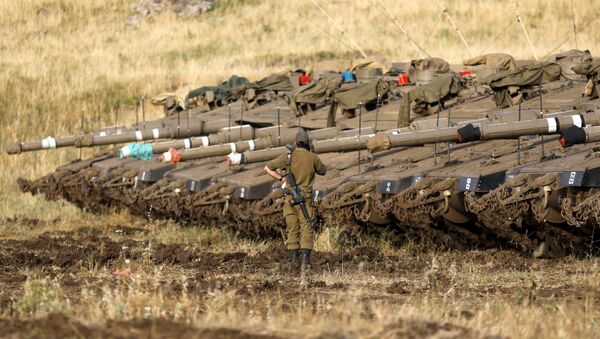 Израильский солдат рядом с танками Merkava Mark IV в районе развертывания вблизи сирийской границы (10 мая 2018). Голанские высоты - Sputnik Армения