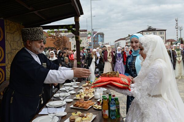 Невеста принимает подарок от гостей во время церемонии массового бракосочетания 200 пар, проводимой в рамках празднования 200-летия города (5 октября 2018). Грозный - Sputnik Армения