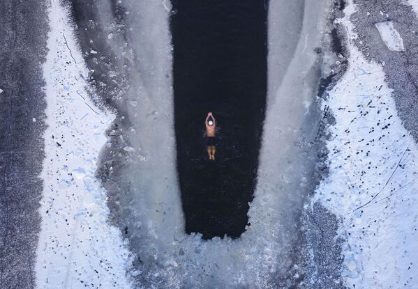 Человек плавает в частично замерзшем озере в Шэньяне, провинция Ляонин - Sputnik Армения