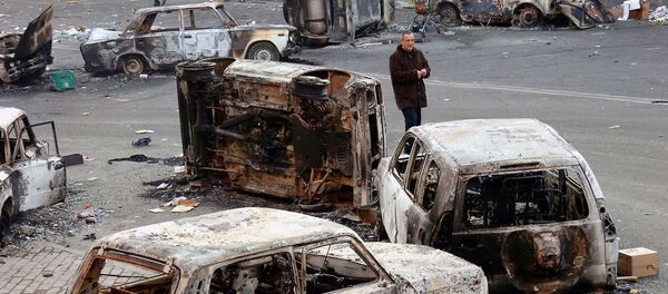 Мужчина среди сожженных автомобилей, оставленных после ночных беспорядков (2 марта 2008). Еревaн - Sputnik Армения