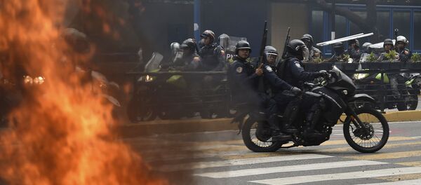 Спецназовцы на мотоцикле проезжают мимо пожара во время акции протеста против правительства президента Николаса Мадуро (23 января 2019). Каракас - Sputnik Армения