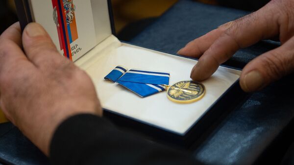 Медаль За боевые заслуги Айка Карамяна в руках отца во время церемонии награждения военнослужащих (28 января 2019). Еревaн - Sputnik Армения