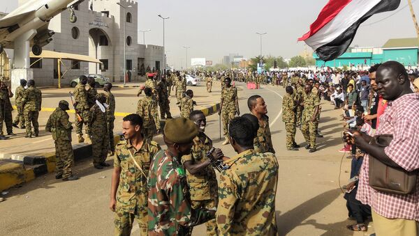 Суданские солдаты стоят на страже бронетранспортеров, а демонстранты продолжают протестовать против режима возле штаба армии в столице Судана (11 апреля 2019). Хартум - Sputnik Армения