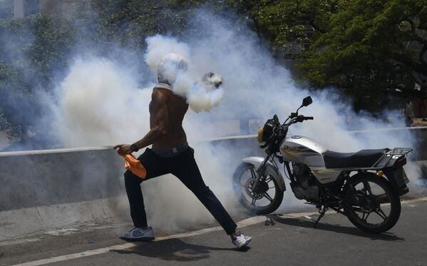 Протестующий кидает бутылку со слезоточивым газом во время столкновения с Национальной гвардией Венесуэлы в Альтамире, районе Каракаса - Sputnik Армения