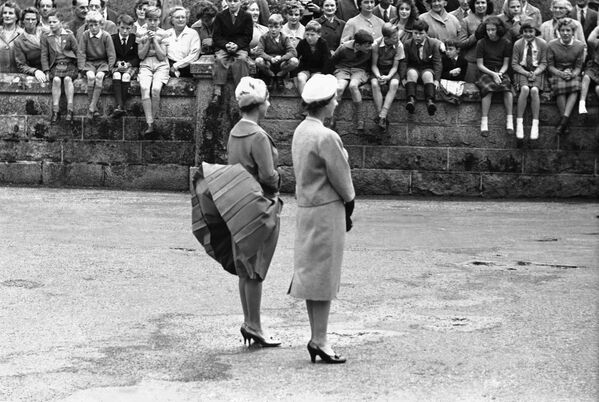 Ветер поднимает юбку принцессы Маргарет, пока они с королевой Елизаветой Второй ожидают прибытия президента США Дуайта Эйзенхауэра в замке Балморал, Шотландия - Sputnik Армения