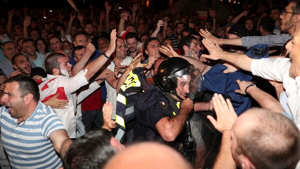 Участники акции протеста против визита российской делегации возле здания парламента Грузии окружили полицейского (20 июня 2019). Тбилиси - Sputnik Армения