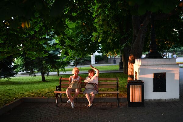 Отдыхающие сидят на скамейке в парке в Севастополе в Крыму - Sputnik Армения