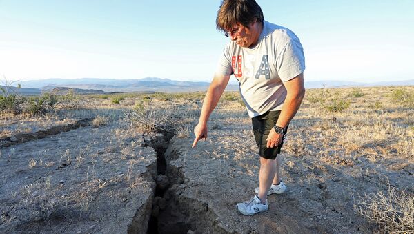 Мужчина показывает расщелину, которая открылась в пустыне после мощного землетрясения недалеко от города Риджкрест (4 июля 2019). Калифорния - Sputnik Армения