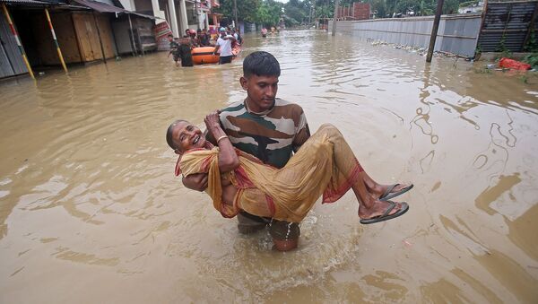 Член TSR переносит пострадавшую от наводнения женщину в более безопасное место после сильных дождей в деревне Балдахал (14 июля 2019). Индия - Sputnik Արմենիա