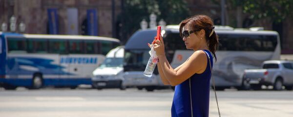 Туристка записывает на видео веселье на площади Республики во время праздника Вардавар (28 июля 2019). Еревaн - Sputnik Արմենիա