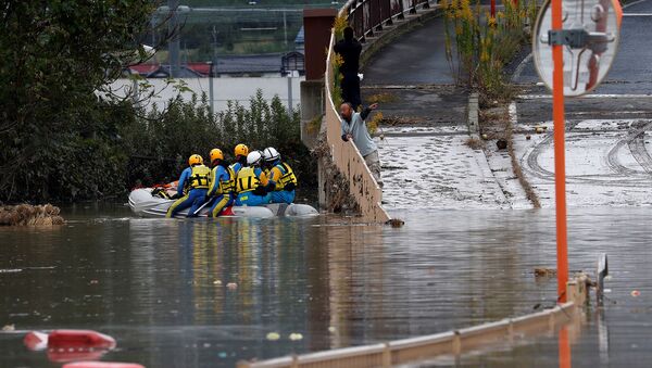 Мужчина разговаривает со спасателями, обыскивающими затопленный район после тайфуна Хагибис (14 октября 2019). Япония - Sputnik Армения