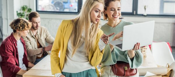 Девушки в офисе обсуждают проект рассматривая изображение на ноутбуке - Sputnik Армения