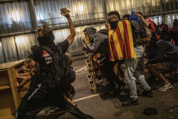 Протестующий с камнем во время столкновения с полицией в аэропорту Эль-Прат в Барселоне - Sputnik Армения