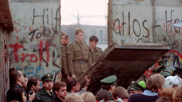 Восточногерманские пограничники видны через щель в Берлинской стене после того, как демонстранты снесли сегмент стены у Бранденбургских ворот (11 ноябрq 1989). Берлин - Sputnik Արմենիա