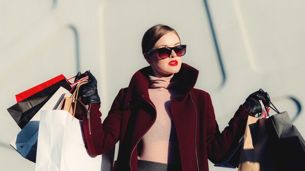 Красивая ухоженная женщина в солнцезащитных очках, красной помаде и бордовом пальто с многочисленными покупками - Sputnik Армения