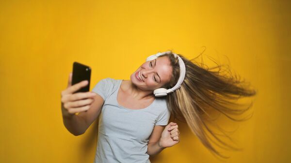 Девушка в наушниках со смартфоном веселится слушая музыку  - Sputnik Армения