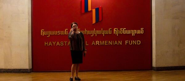 Женщина с телефоном у логотипа Всеармянского фонда Айастан Женщина с телефоном у логотипа Всеармянского фонда Айастан - Sputnik Армения