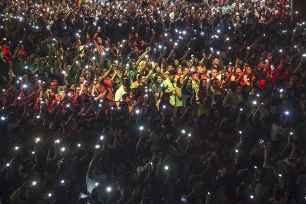 Христиане с зажженными фонарями на телефонах во время рождественской мессы в Индонезии - Sputnik Армения