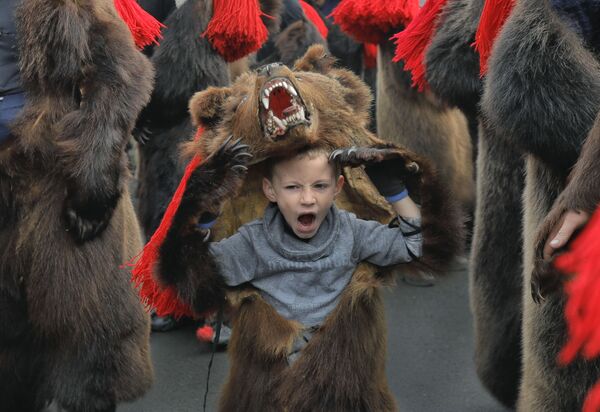 Зевающий мальчик в костюме медведя на новогоднем шествии в румынском городе Комэнешти - Sputnik Армения