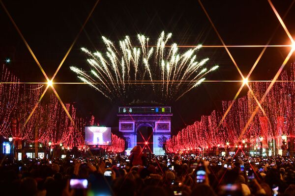 Люди фотографируют фейерверк над Триумфальной аркой во время празднования Нового года на Елисейских Полях в Париже, Франция - Sputnik Армения