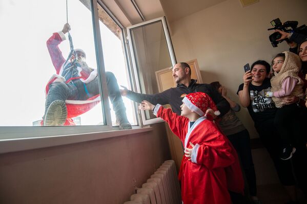 Дед Мороз - альпинист залезает в окно комнаты с ожидающими детьми - Sputnik Армения