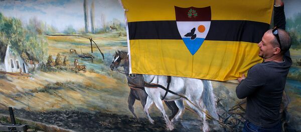 Мужчина закрепляет флаг Либерленда на стене частного дома в Бэки-Моносторе (1 мая 2015). Сербия - Sputnik Արմենիա