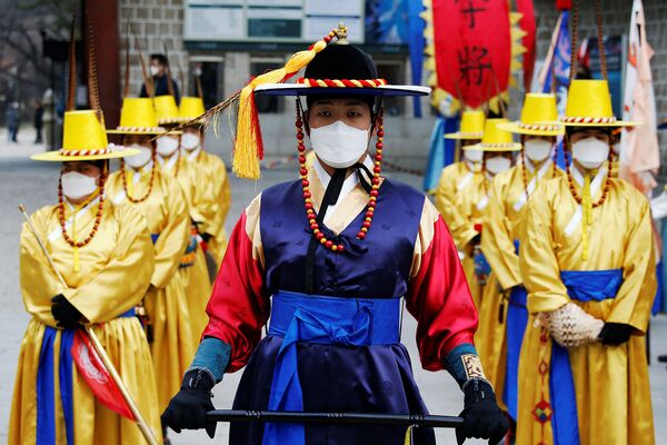 Рабочие в корейских традиционных костюмах и защитных масках во время реконструкции церемонии смены Королевской гвардии перед Дворцом Деоксу (31 января 2020). Сеул - Sputnik Армения