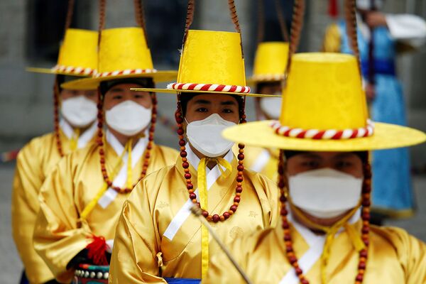 Рабочие в корейских традиционных костюмах и защитных масках во время реконструкции церемонии смены Королевской гвардии перед Дворцом Деоксу (31 января 2020). Сеул - Sputnik Армения